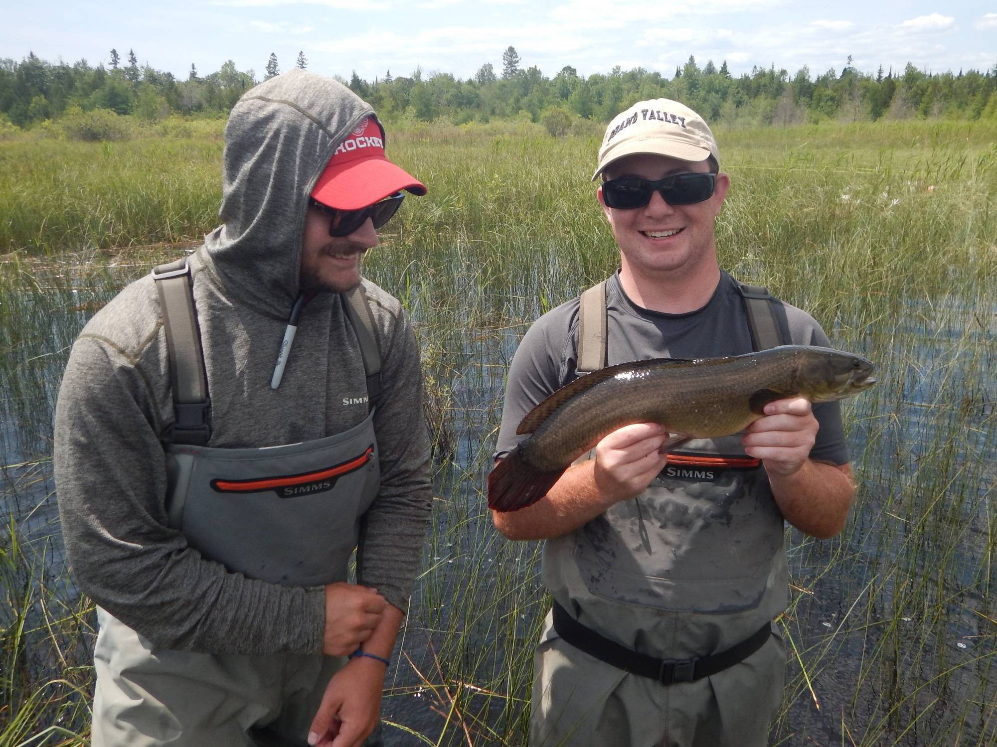 Alan Mock displays a bowfin for the camera while Bert Carey looks on.